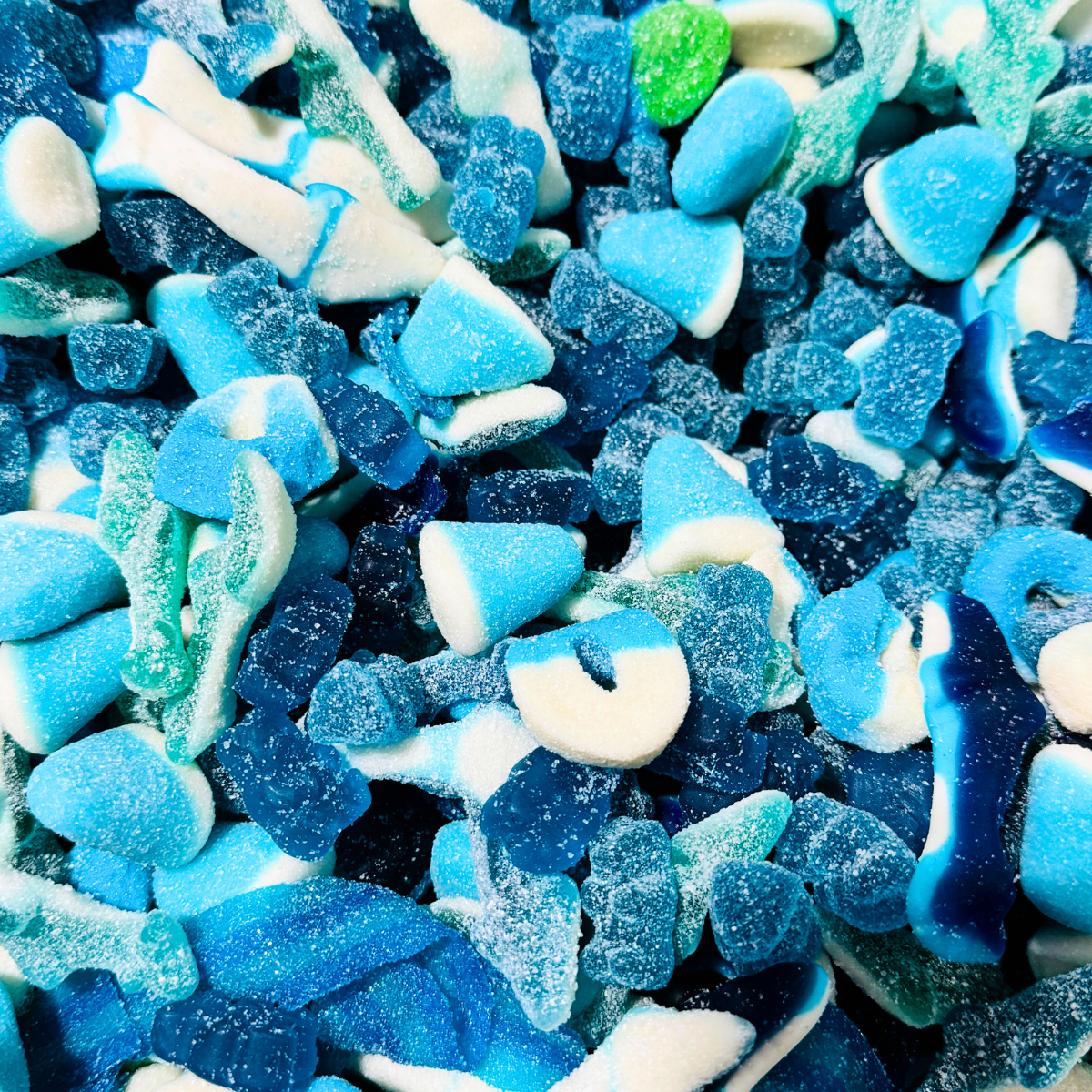 Close-up of assorted blue raspberry gummy candies including sharks, belts, and sour gummies