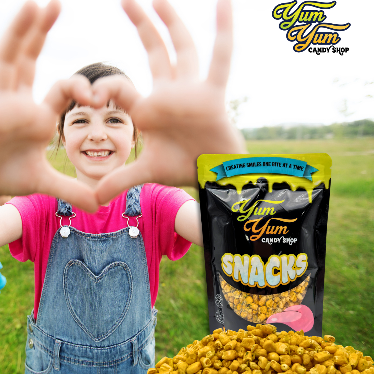 Child making a heart shape with hands, Yum Yum Snacks packaging, and field background
