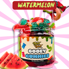Watermelon flavor Gooey Gummies jar surrounded by fresh watermelon slices and green leaves.