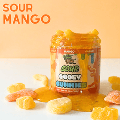 Sour Mango Gooey Gummies jar and orange thick syrup on an orange background