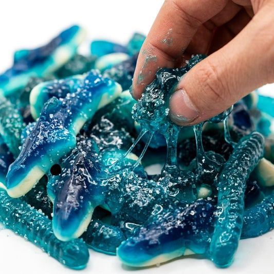 A hand picking up a pile of sour blue raspberry gooey gummies without a spoon