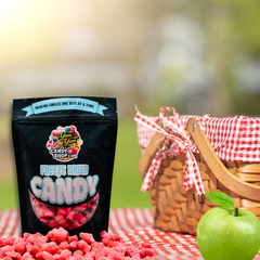 Bag of freeze dried apple cinnamon hotties on picnic table with apples and basket