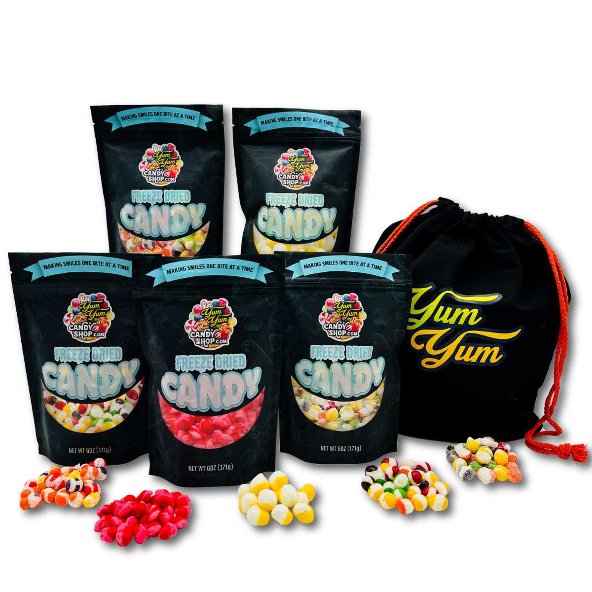 A collection of freeze-dried candy varieties from Yum Yum Candy Shop, including bags labeled Rainbow Krunchies, Sour Lemon Balls, and others, displayed alongside a custom Yum Yum drawstring gift tote bag.