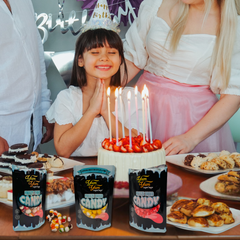 Child celebrating a birthday with cake and Yum Yum Candy Shop freeze dried candy packages on a party table