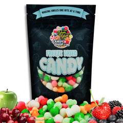A bag of Fruity Air Krunch Bites freeze-dried candy snack with various colorful candies visible through the packaging window, presented with fresh fruits around it.