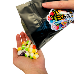 Hand pouring colorful freeze-dried candies from resealable bag.