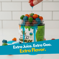 Jar of colorful gummy candies with a hand pouring more gummy candies, against a white tiled wall background.