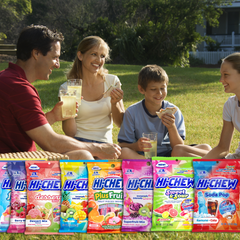 Family sharing Hi-Chew candy outdoors at a picnic.