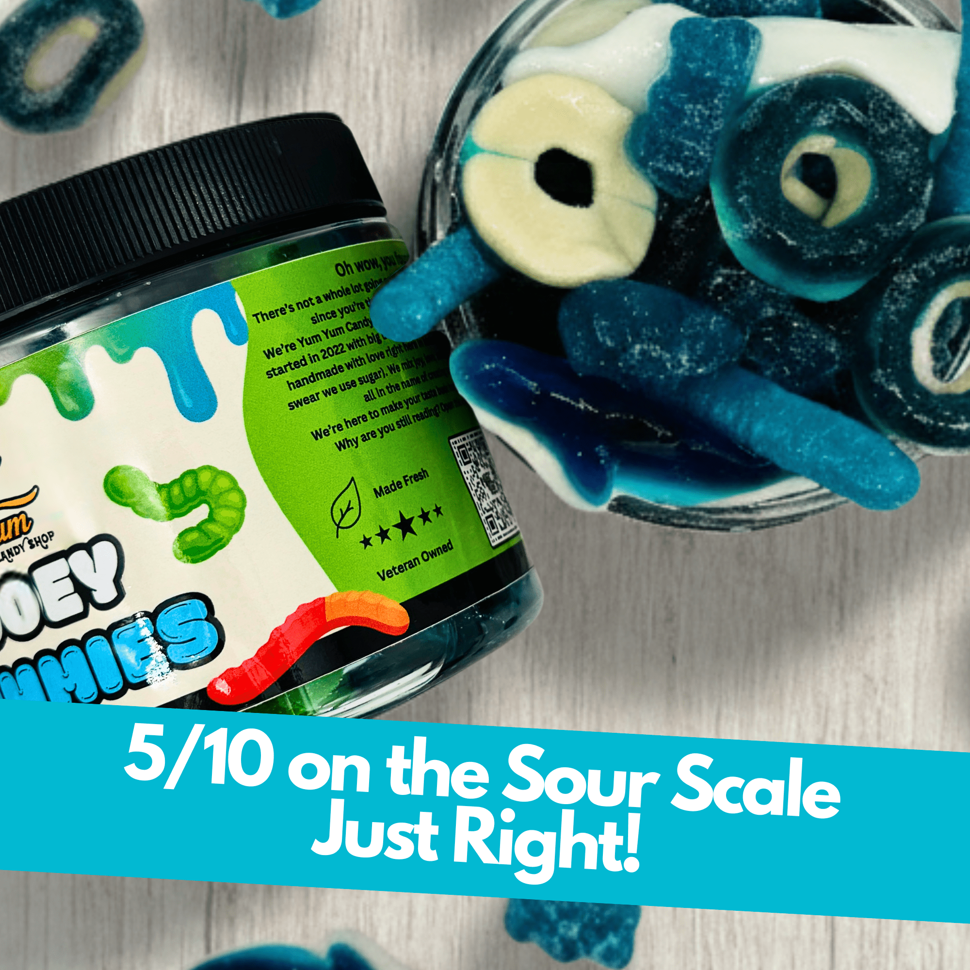 Jar and bowl of sour blue raspberry gooey gummies with sour scale rating text on a wooden background