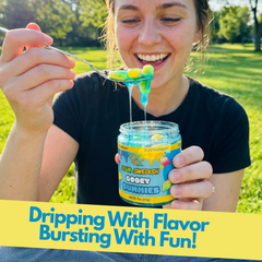A woman outdoors smiling as she holds the jar and lifts a spoonful of the blue-syrup-covered gummies. Yellow text overlay reads: "Dripping With Flavor Bursting With Fun!"