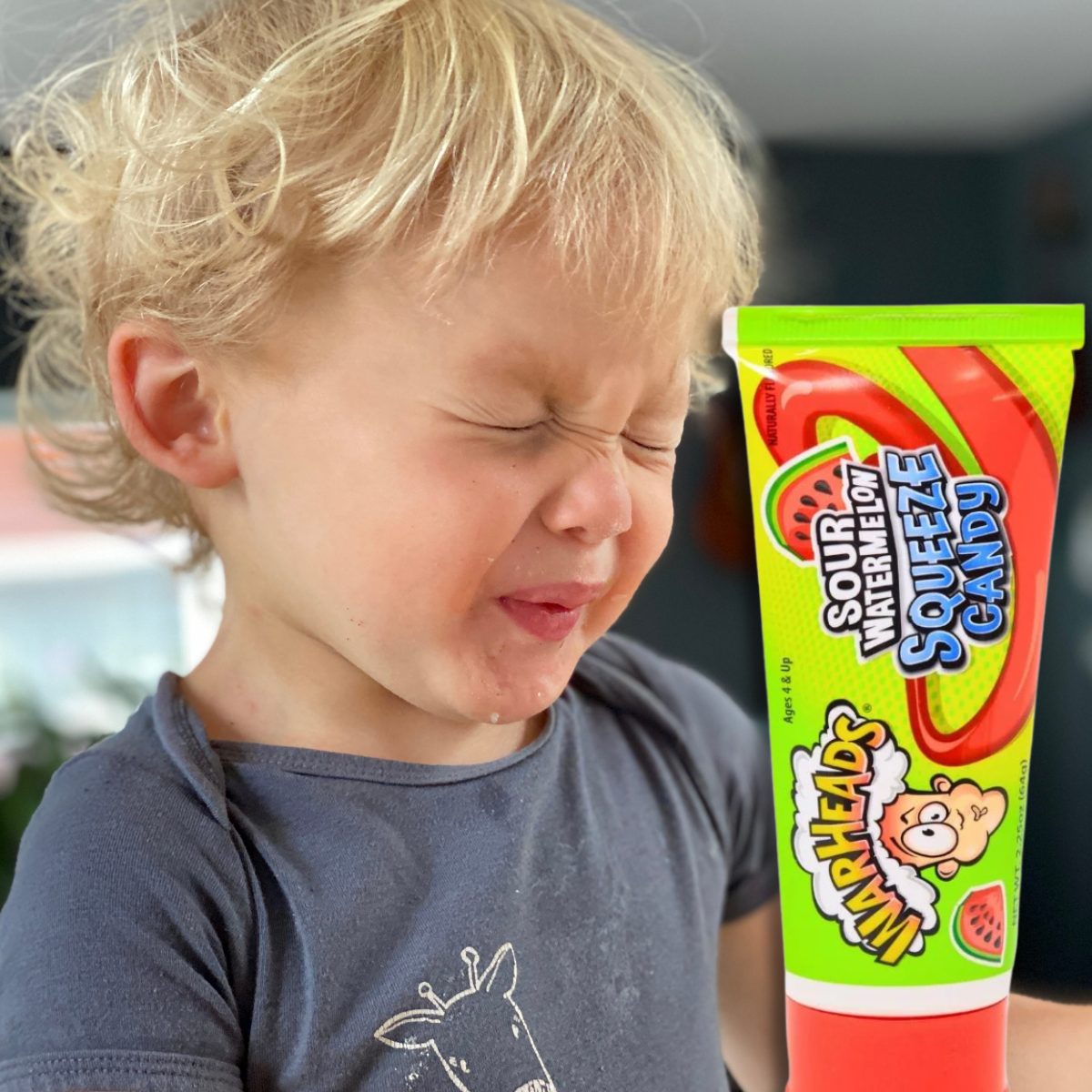 Child making a sour face with a tube os warheads sour candy